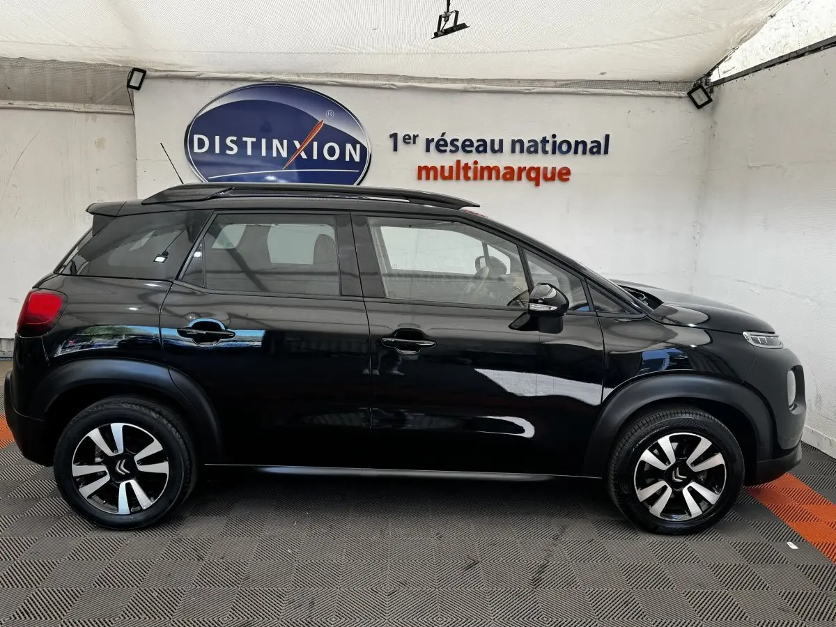 Vue latérale droite d'un Citroën C3 Aircross noir, avec jantes alliage bicolores et barres de toit noires visibles.