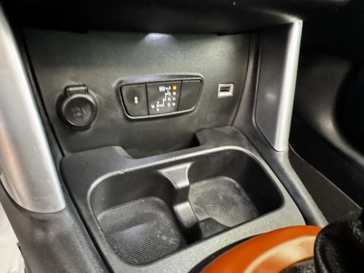Gros plan sur la console centrale noire de la Citroën C3 Aircross 2020, avec prise 12V, port USB et rangement double.
