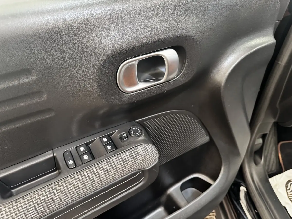 Gros plan sur la porte côté conducteur noire de la Citroën C3 Aircross 2020 avec commandes de vitres et poignée argentée.