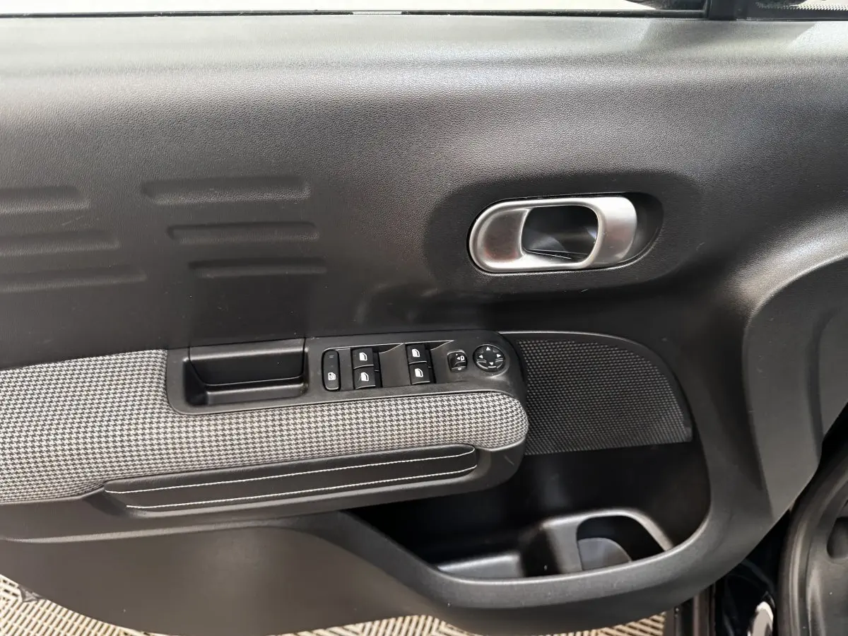 Gros plan sur la porte avant gauche noire du Citroën C3 Aircross 2020 avec commandes de vitres et poignée intérieure chromée.
