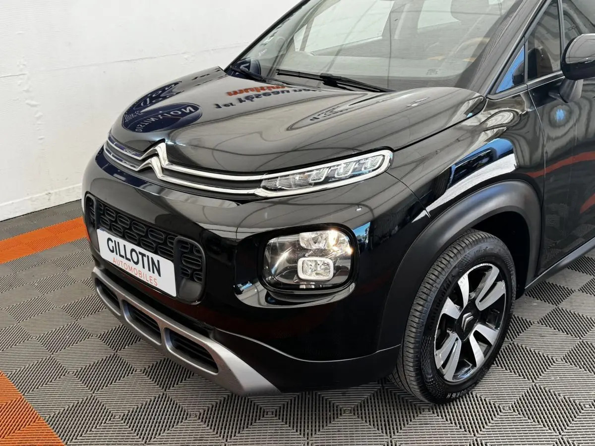 Vue 3/4 avant droit d'un Citroën C3 Aircross noir brillant avec feux LED et jantes alliage bicolores.