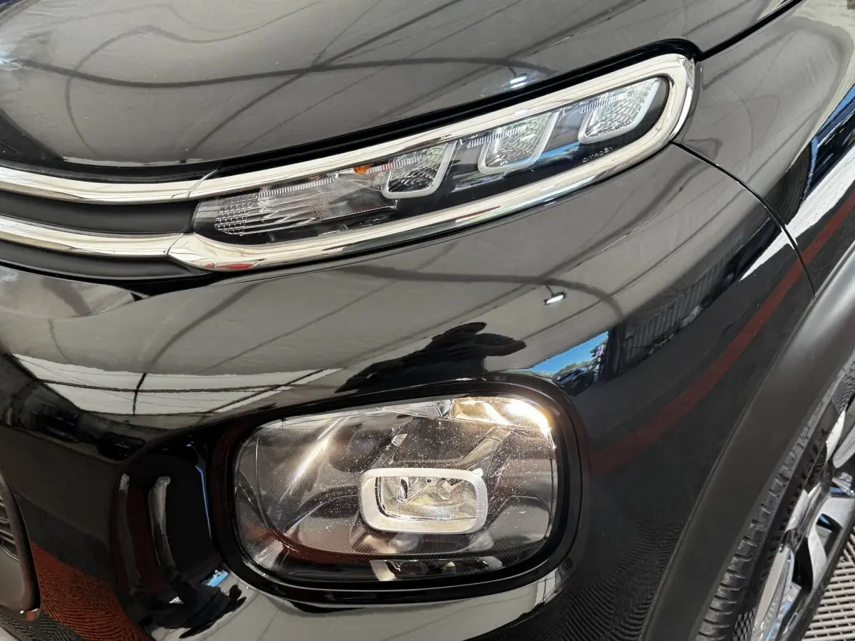 Gros plan sur le phare avant droit noir brillant du Citroën C3 Aircross 2020 avec détails LED et carrosserie lisse.