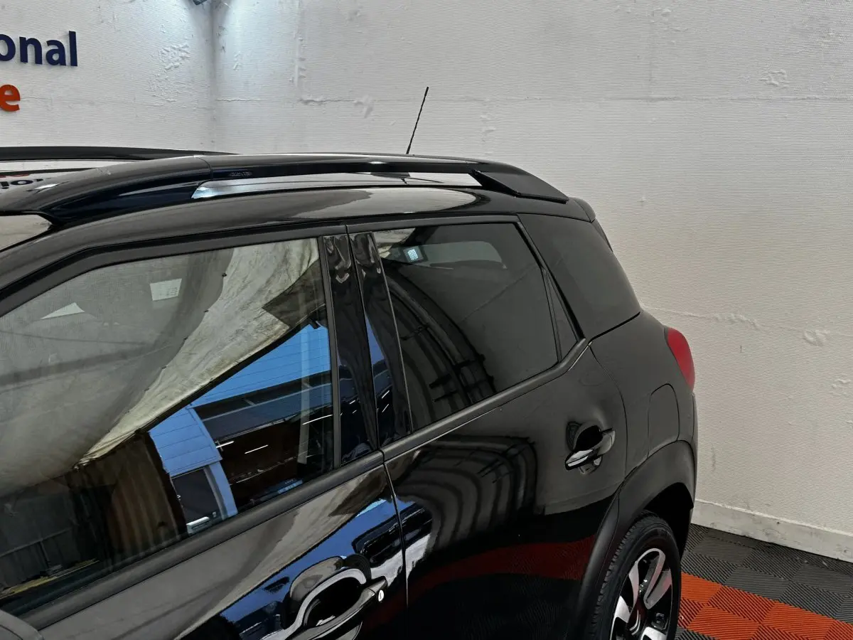 Vue latérale arrière droite d'un Citroën C3 Aircross noir avec barres de toit et jantes alliage visibles.