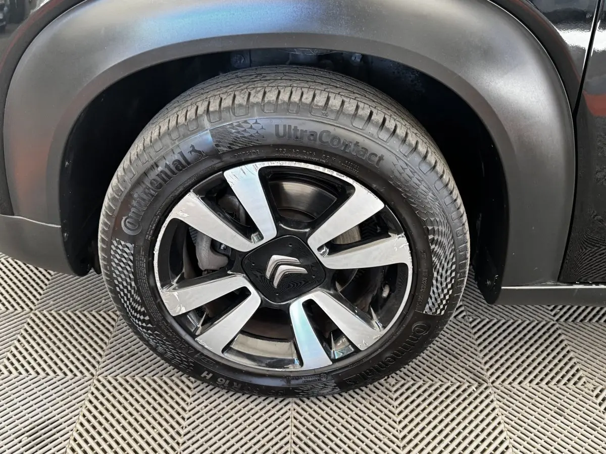 Gros plan sur la roue avant droite noire d'une Citroën C3 Aircross 2020 avec jante alliage et logo Citroën central.