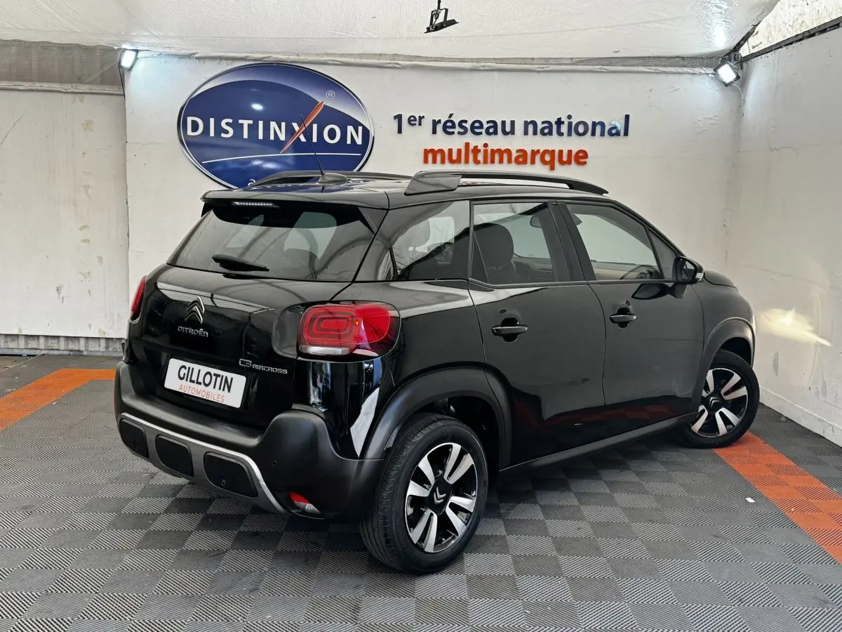 Vue 3/4 arrière droite d'un Citroën C3 Aircross noir avec barres de toit et jantes distinctives en concession.