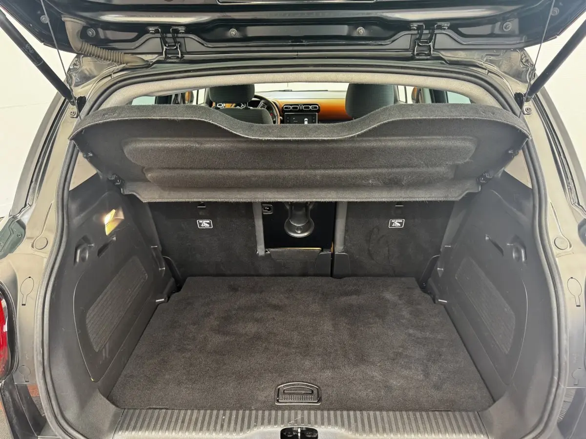 Coffre ouvert vu de l'arrière d'une Citroën C3 Aircross noire, montrant l'espace de chargement et la tablette de séparation.