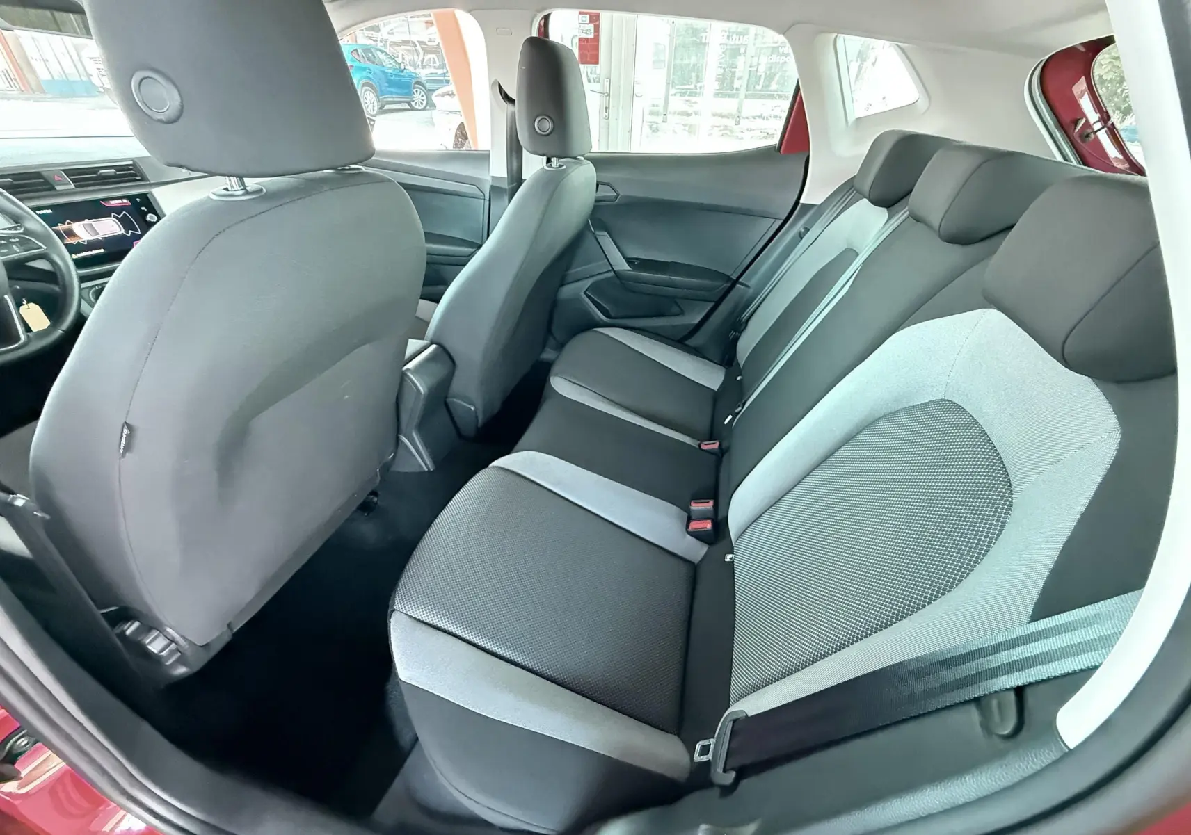 Vue intérieure arrière côté droit de la SEAT Ibiza rouge passion, montrant les sièges arrière en tissu gris et noir.