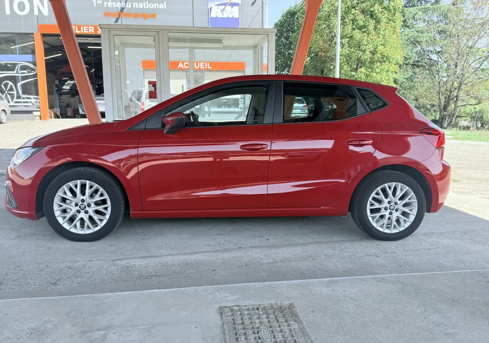 Profil latéral droit d'une SEAT Ibiza rouge passion métal 5 portes, avec jantes alliage et rétroviseurs assortis.
