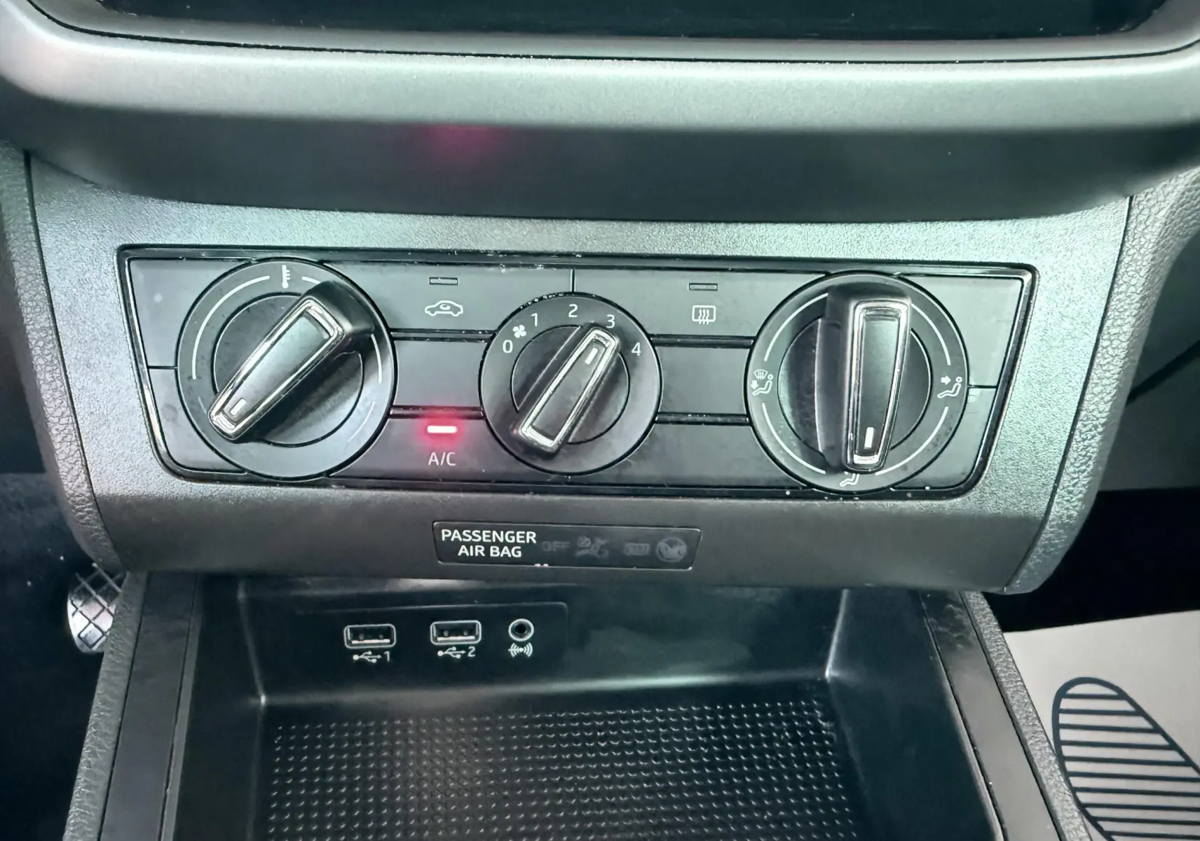 Gros plan sur les commandes de climatisation et les ports USB du tableau de bord d’une SEAT Ibiza rouge passion.