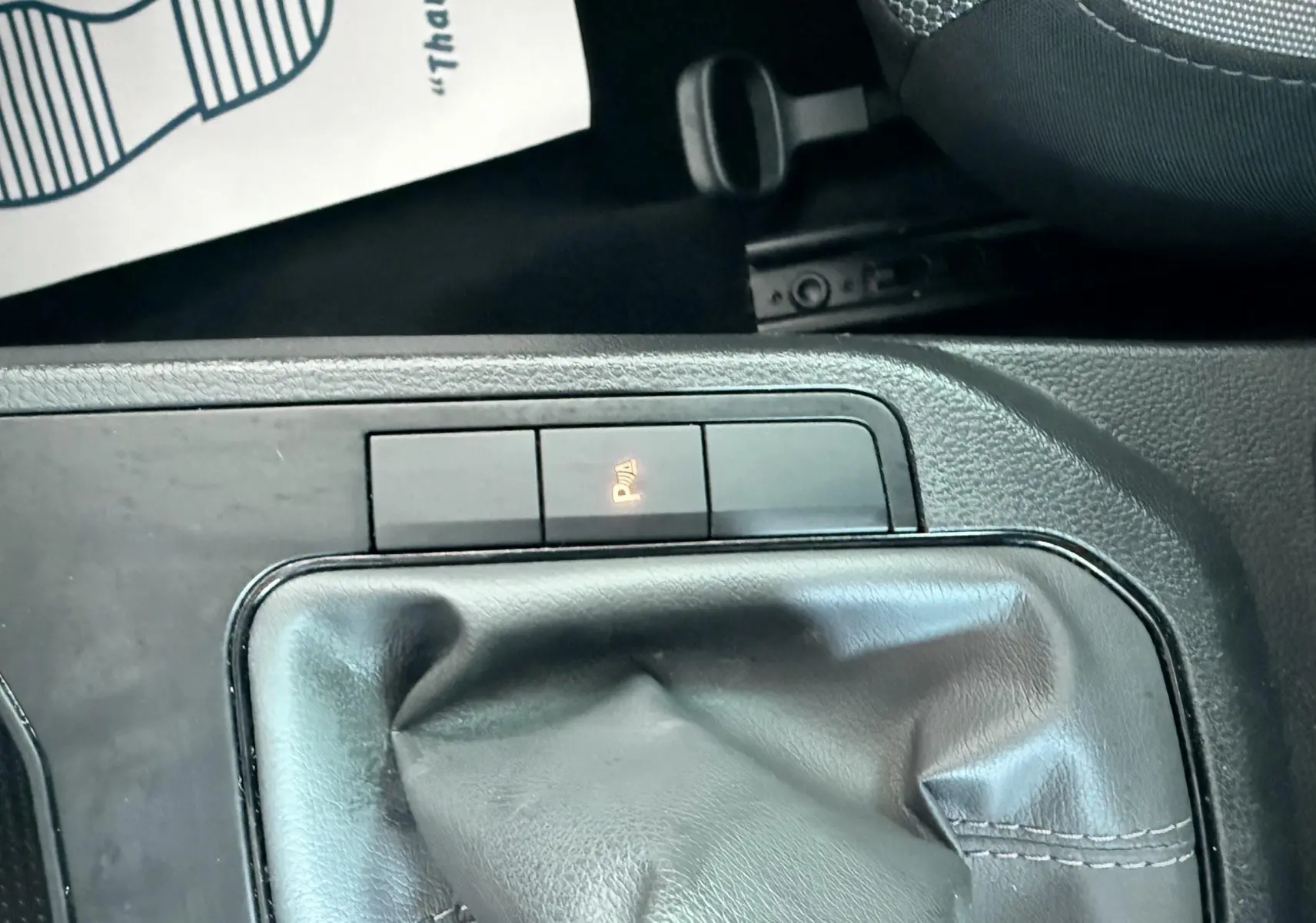 Gros plan sur le levier de vitesses manuel et les boutons de commande du frein de stationnement dans une SEAT Ibiza rouge passion.
