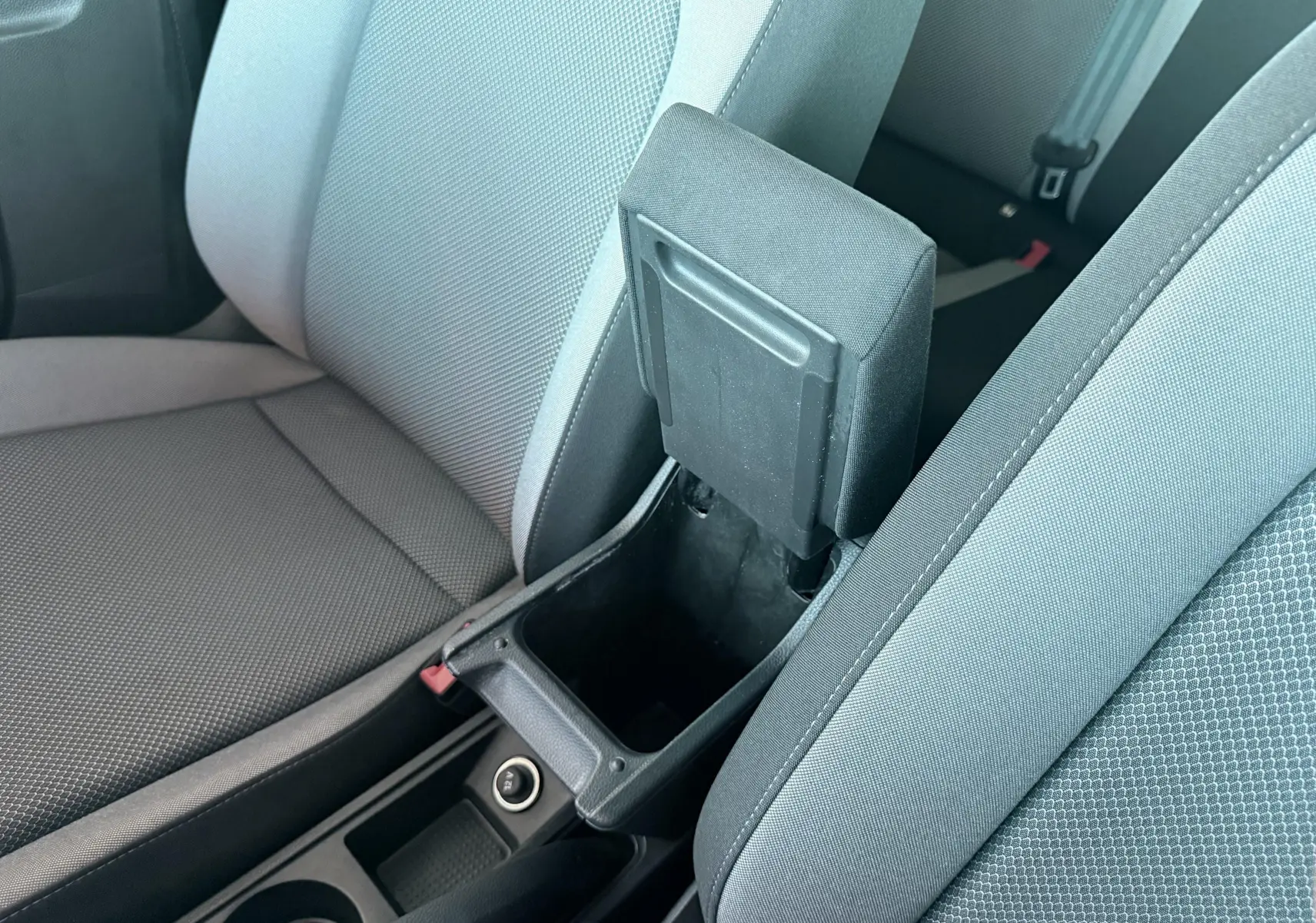 Vue rapprochée de l'accoudoir central ouvert entre les sièges avant gris clair et foncé d'une SEAT Ibiza 2020.
