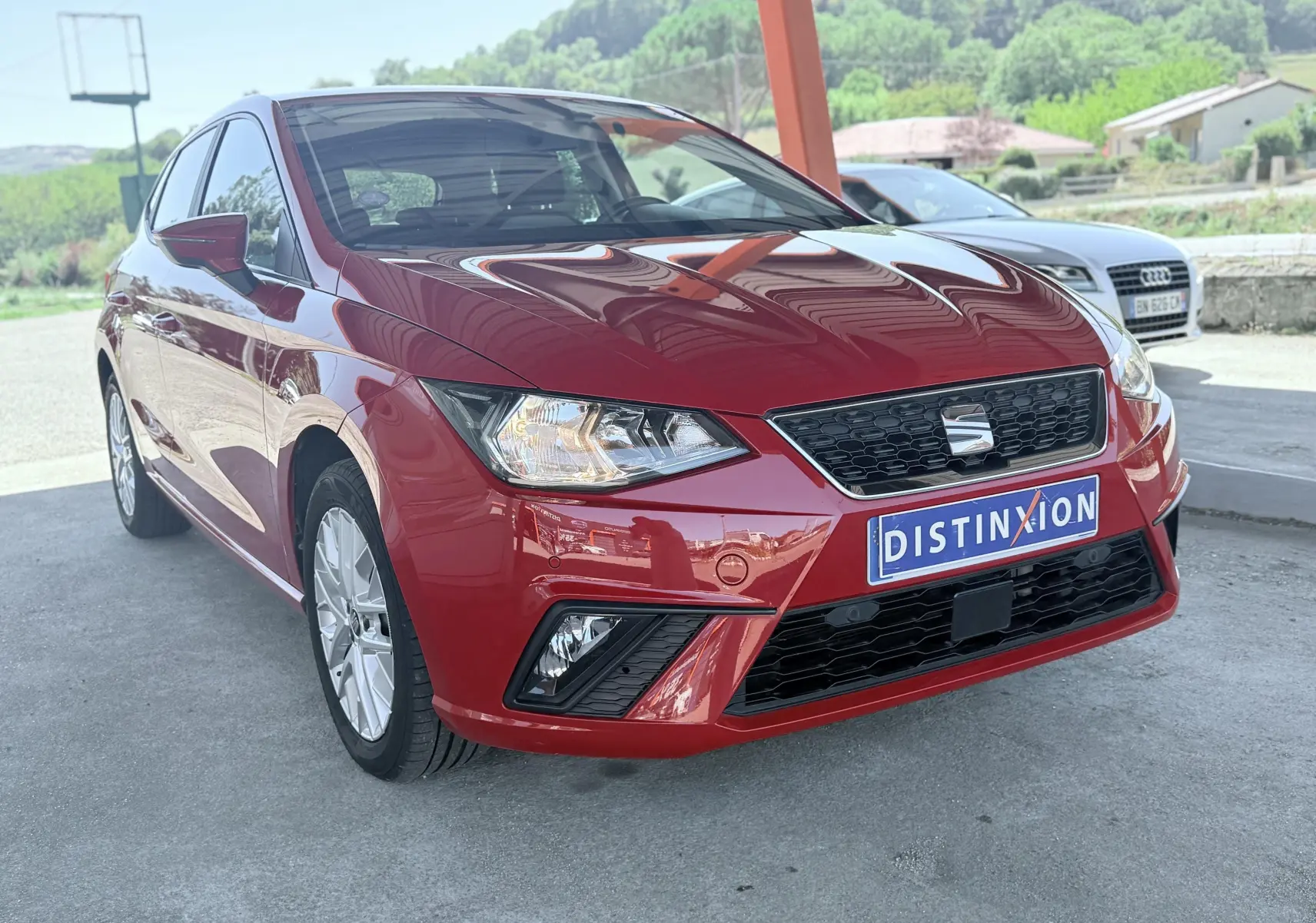 SEAT Ibiza rouge passion vue 3/4 avant droit, avec calandre noire et phares allumés sous abri.