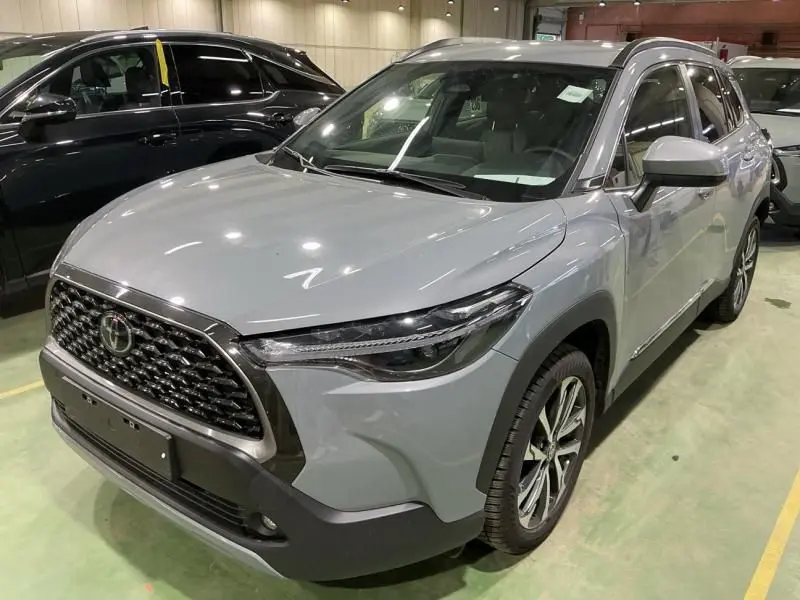 Toyota Corolla Cross gris Manhattan vue 3/4 avant droit, mettant en valeur sa calandre imposante et ses phares LED fins.