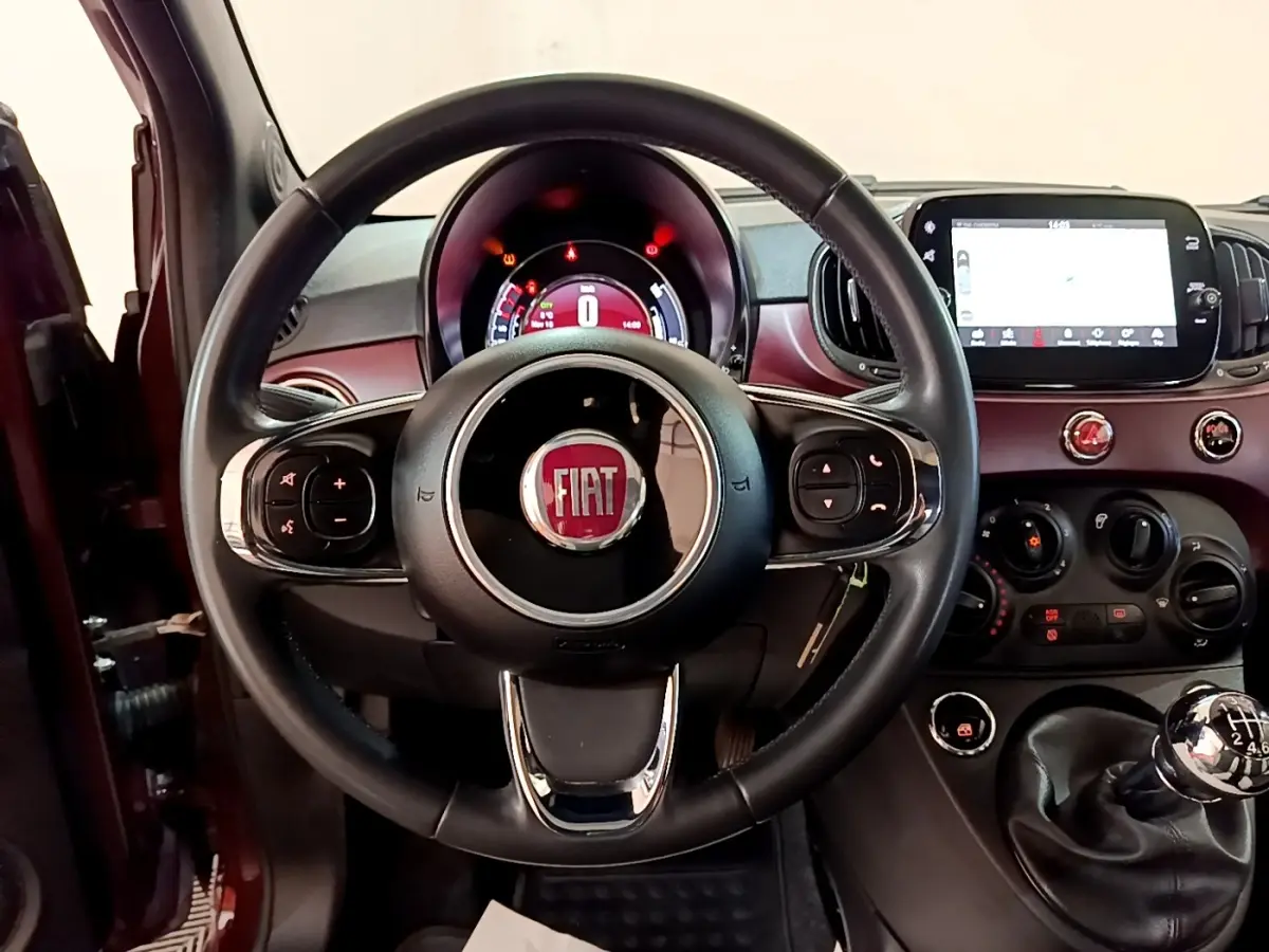 Vue intérieure centrée sur le volant cuir et tableau de bord rouge de la Fiat 500 1.0 70ch BSG Star 2021.