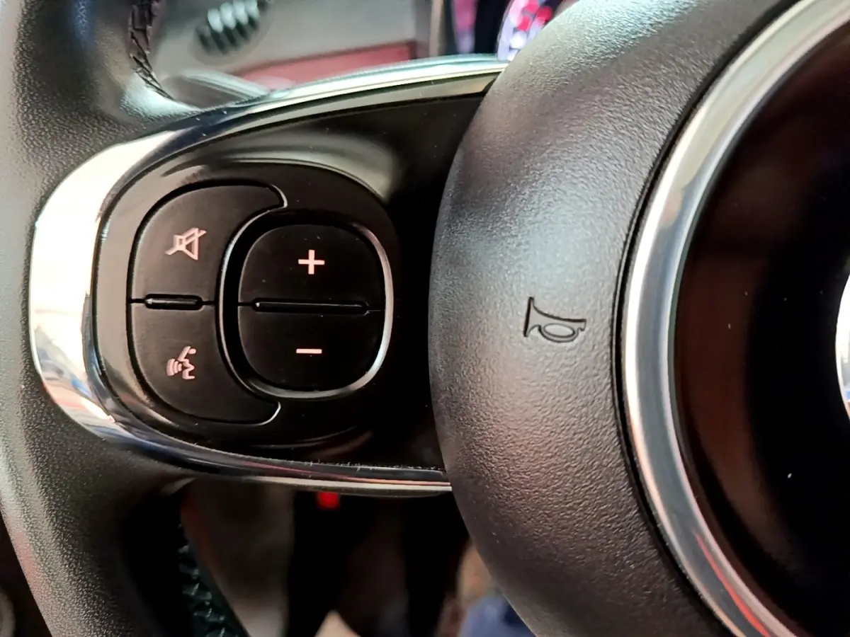 Gros plan sur les commandes gauche du volant cuir de la Fiat 500 rouge 1.0 70ch BSG Star de 2021.