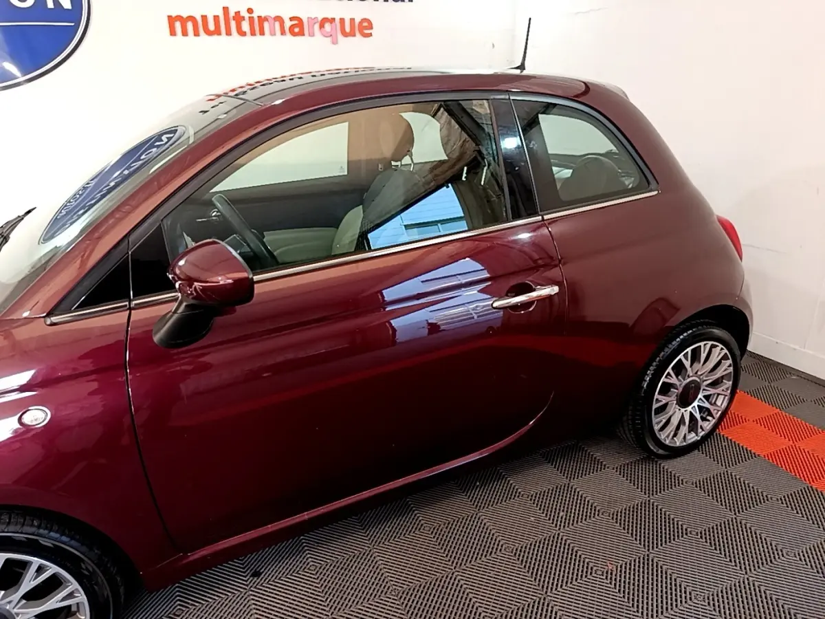 Profil côté gauche d'une FIAT 500 rouge bordeaux 2021 avec jantes alliage et rétroviseurs assortis.