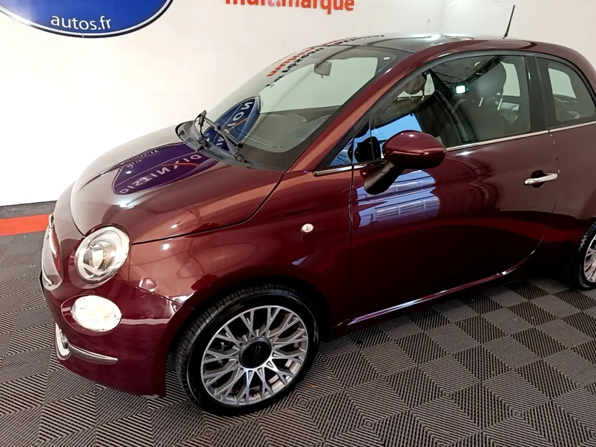 Fiat 500 rouge vue 3/4 avant droit, mettant en valeur ses phares ronds et jantes alliage multibranches.