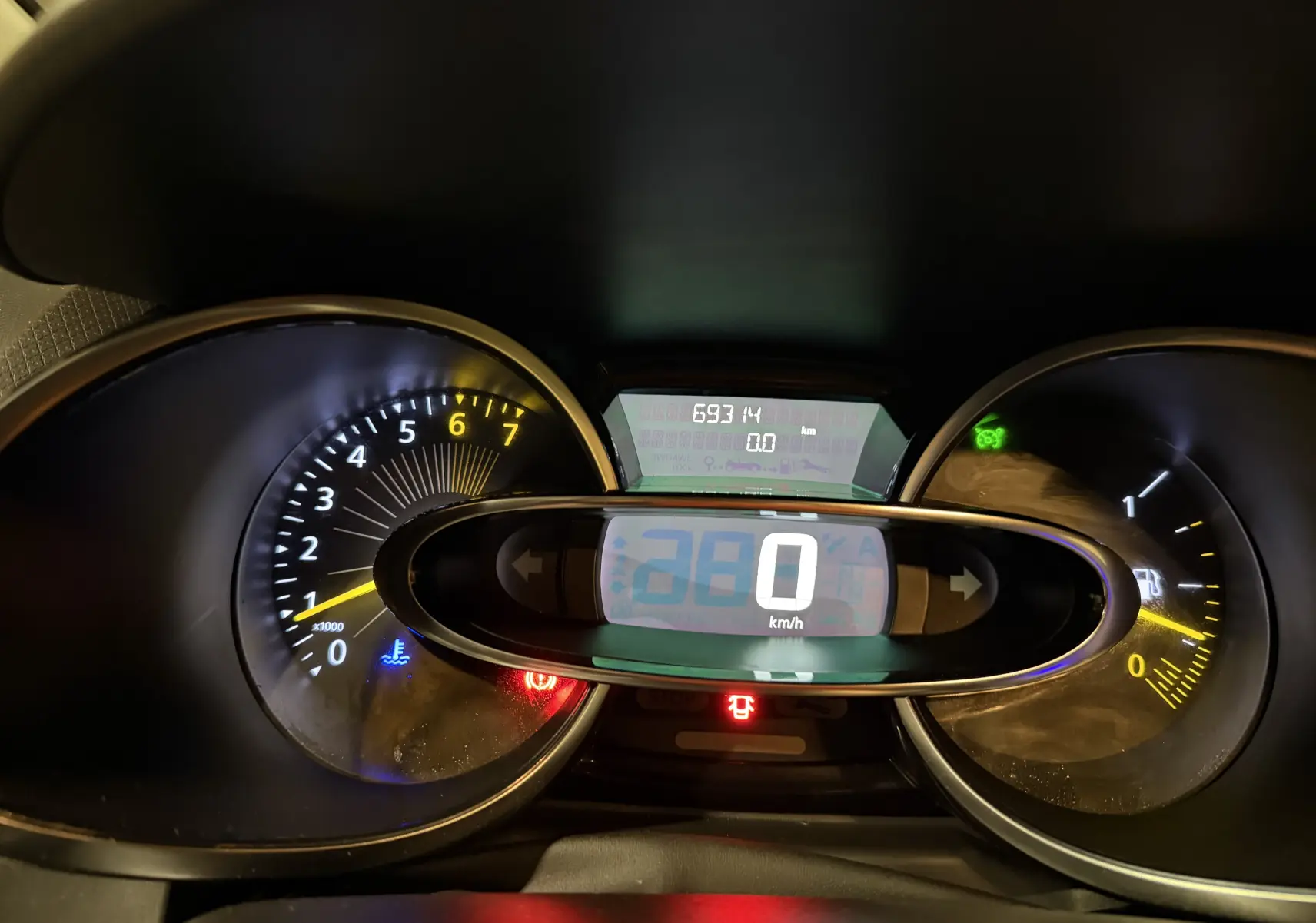 Vue rapprochée du tableau de bord numérique de la Renault Clio Estate IV rouge, affichant 0 km/h et compte-tours.