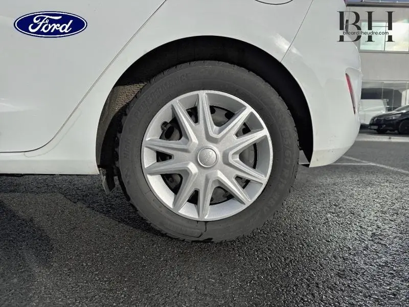 Gros plan sur la roue arrière droite d'une Ford Fiesta blanche Glacier avec enjoliveur étoilé, stationnée sur bitume.