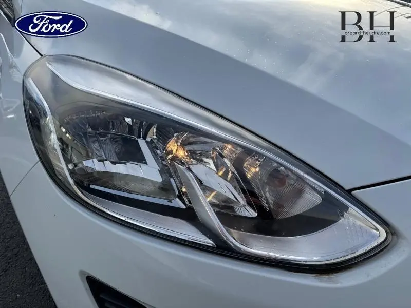 Gros plan sur le phare avant droit blanc glacier d'une Ford Fiesta 2020, mettant en valeur les détails du bloc optique.