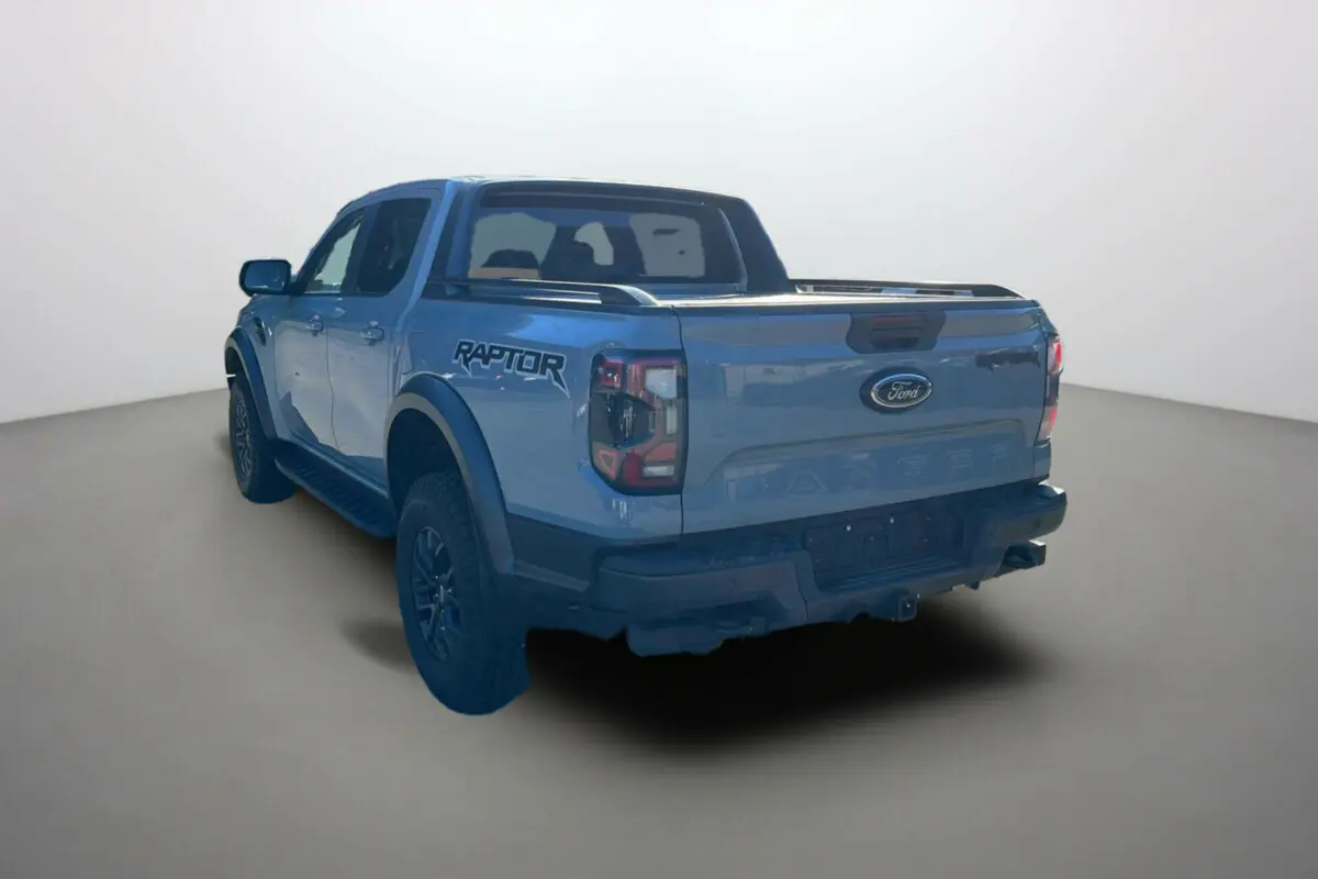 Ford Ranger Raptor gris commandeur vu en 3/4 arrière gauche avec logo Raptor et benne ouverte.