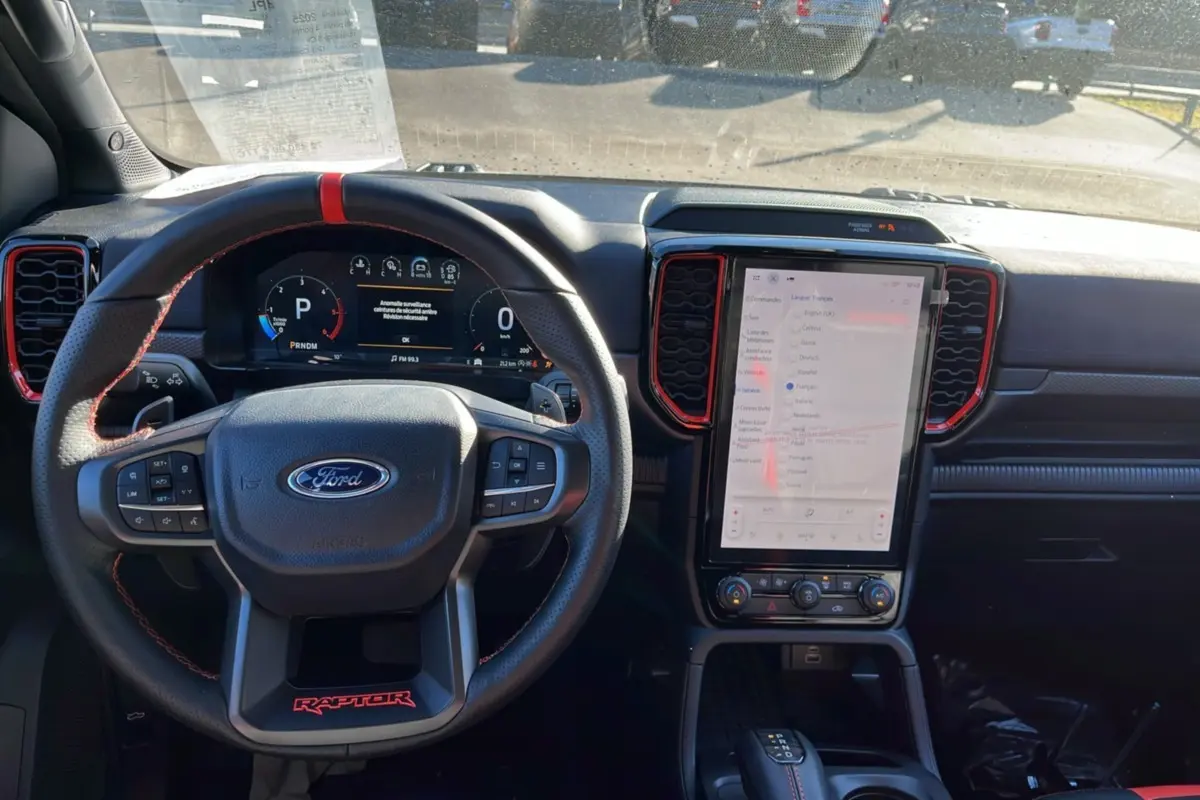 Vue intérieure du tableau de bord du Ford Ranger Raptor 2025, avec volant cuir noir et écran tactile vertical.