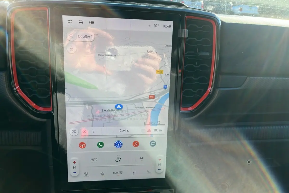 Écran tactile central du Ford Ranger Raptor 2025 avec navigation, entouré de grilles d’aération rouges et tableau de bord noir.