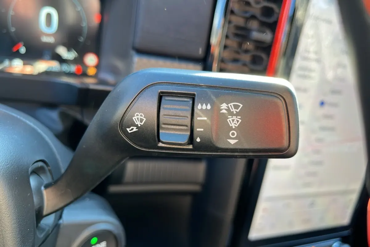 Gros plan sur la commande des essuie-glaces à gauche du volant dans l'habitacle du Ford Ranger Raptor gris commandeur.