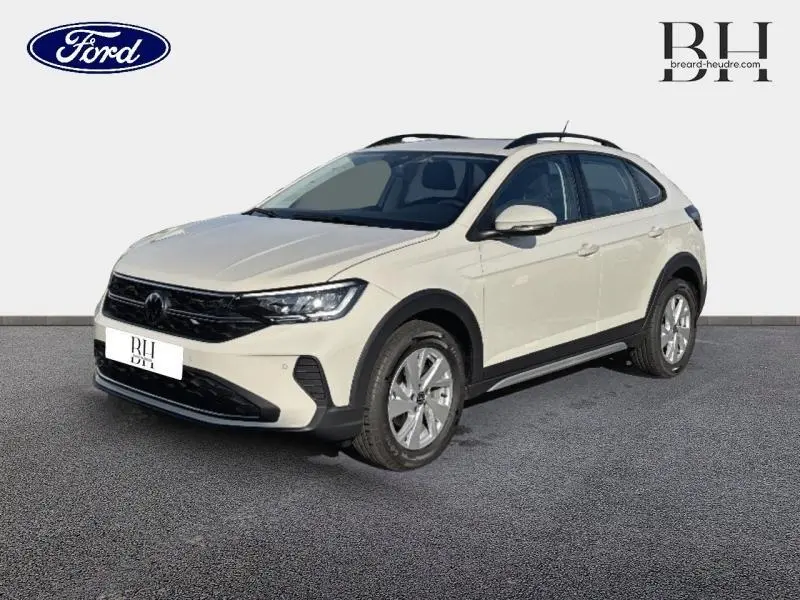 Volkswagen Taigo blanc pur en 3/4 avant droit, avec barres de toit et jantes alliage visibles.