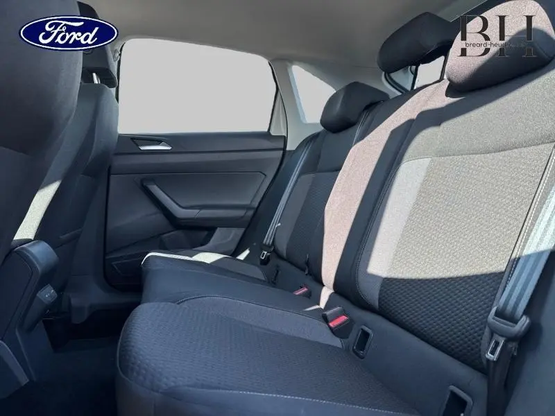 Vue intérieure côté droit des sièges arrière en tissu noir d'un Volkswagen Taigo 2024, avec ceintures et appuie-têtes visibles.