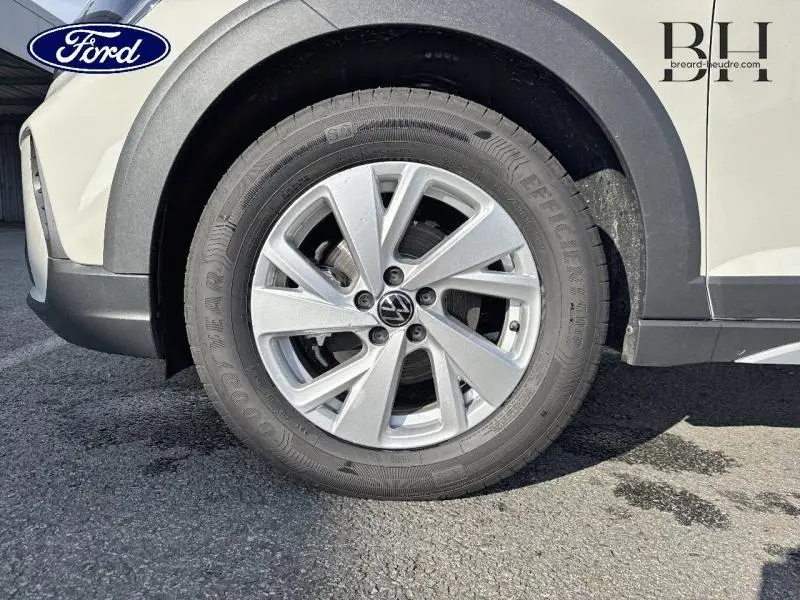 Gros plan sur la roue avant gauche du Volkswagen Taigo blanc Pur, avec jante alu et logo VW au centre.