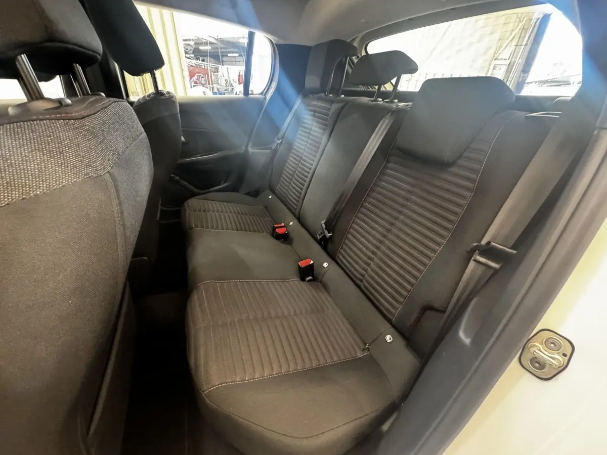Vue intérieure côté droit sur la banquette arrière noire de la Peugeot 208 blanche, avec ceinture et appuie-têtes visibles.