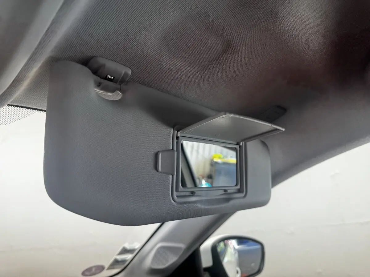 Détail du pare-soleil côté conducteur avec miroir de courtoisie ouvert dans une Peugeot 208 blanche.