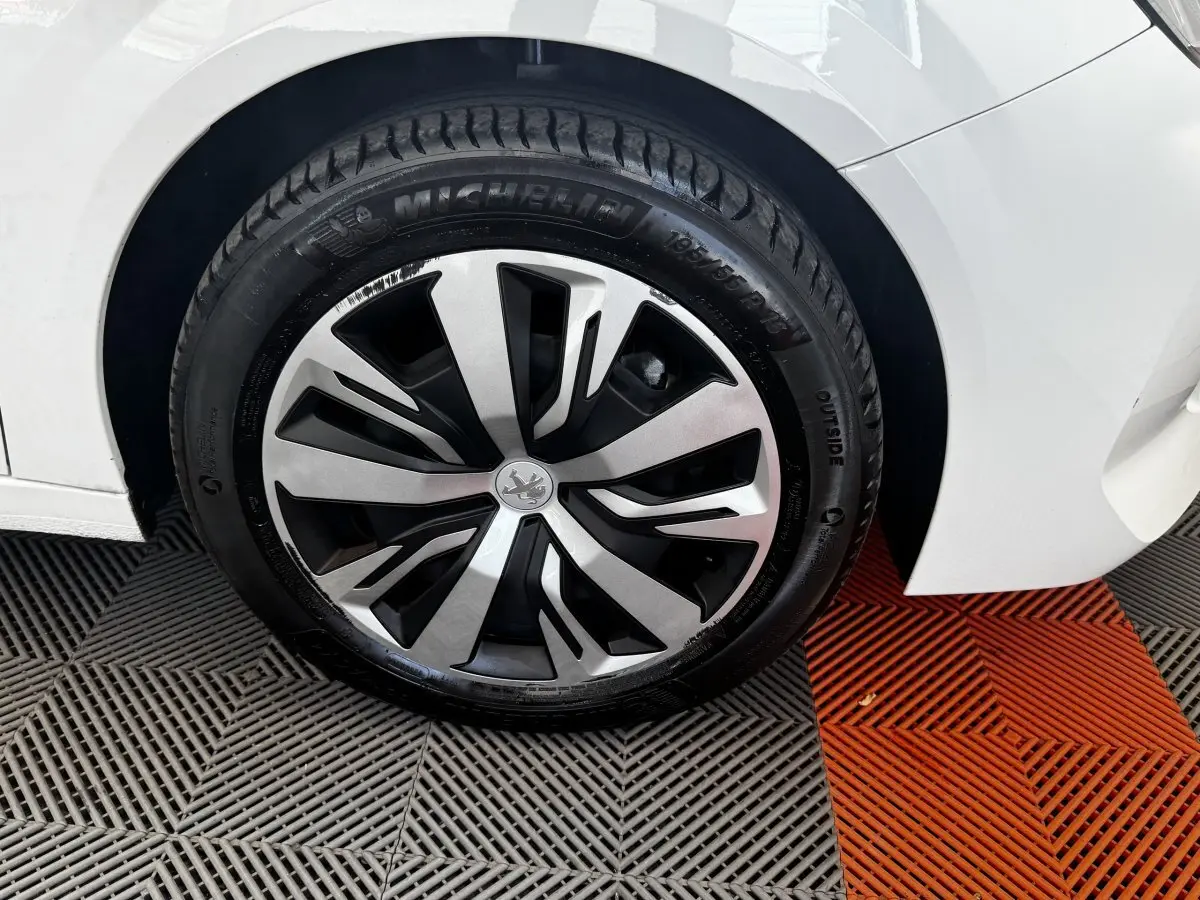 Gros plan sur la roue avant gauche blanche d'une Peugeot 208 PureTech 100 S&S Active Business avec jante spécifique.