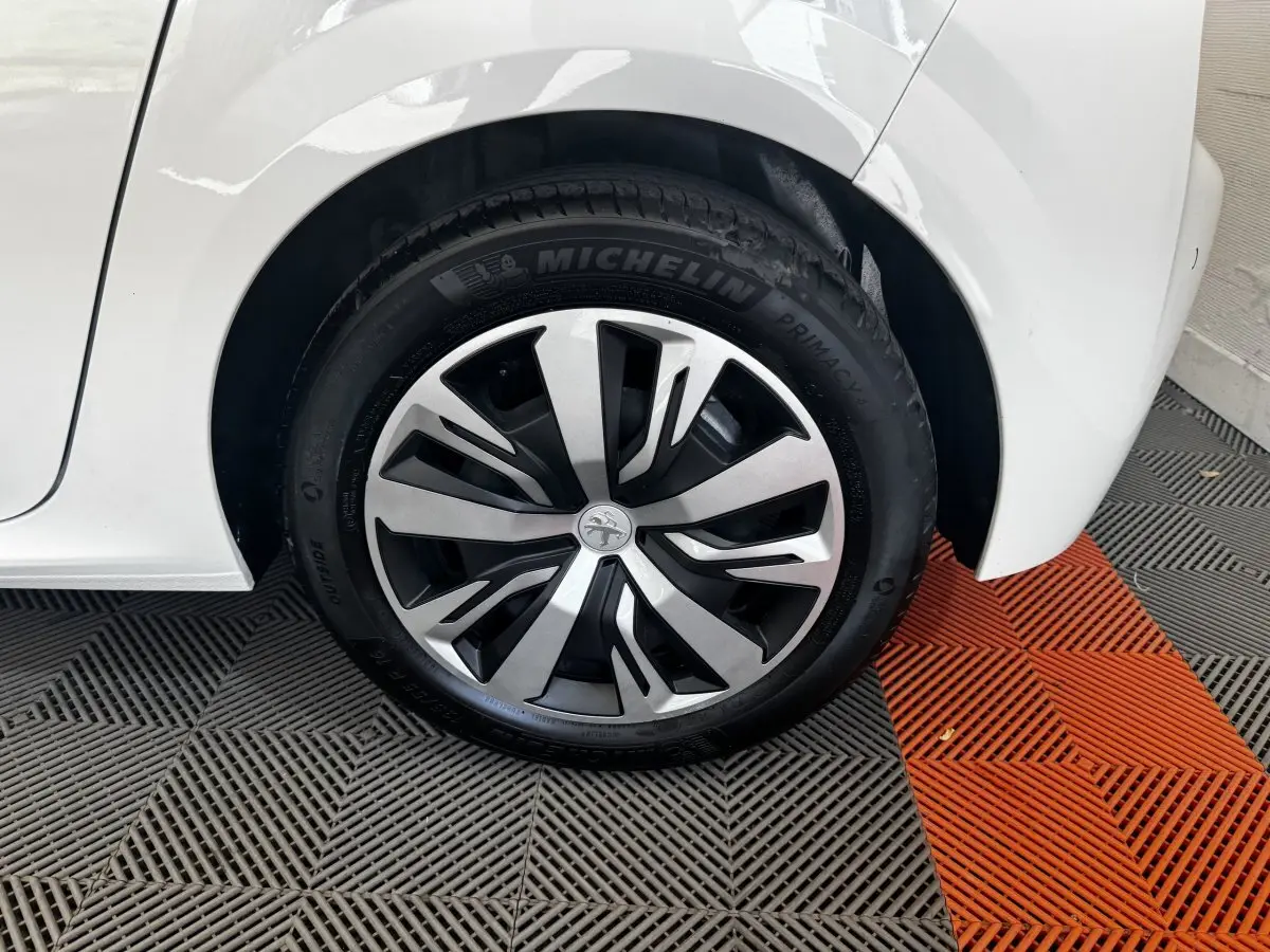 Gros plan sur la roue arrière droite blanche d’une Peugeot 208 avec jante alliage et pneu Michelin.