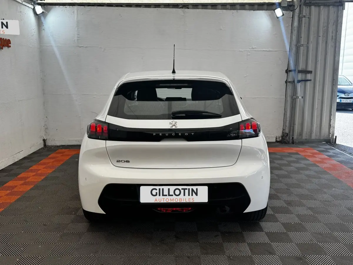 Vue arrière d'une Peugeot 208 blanche 2020 avec feux arrière noirs et logo Peugeot visible.