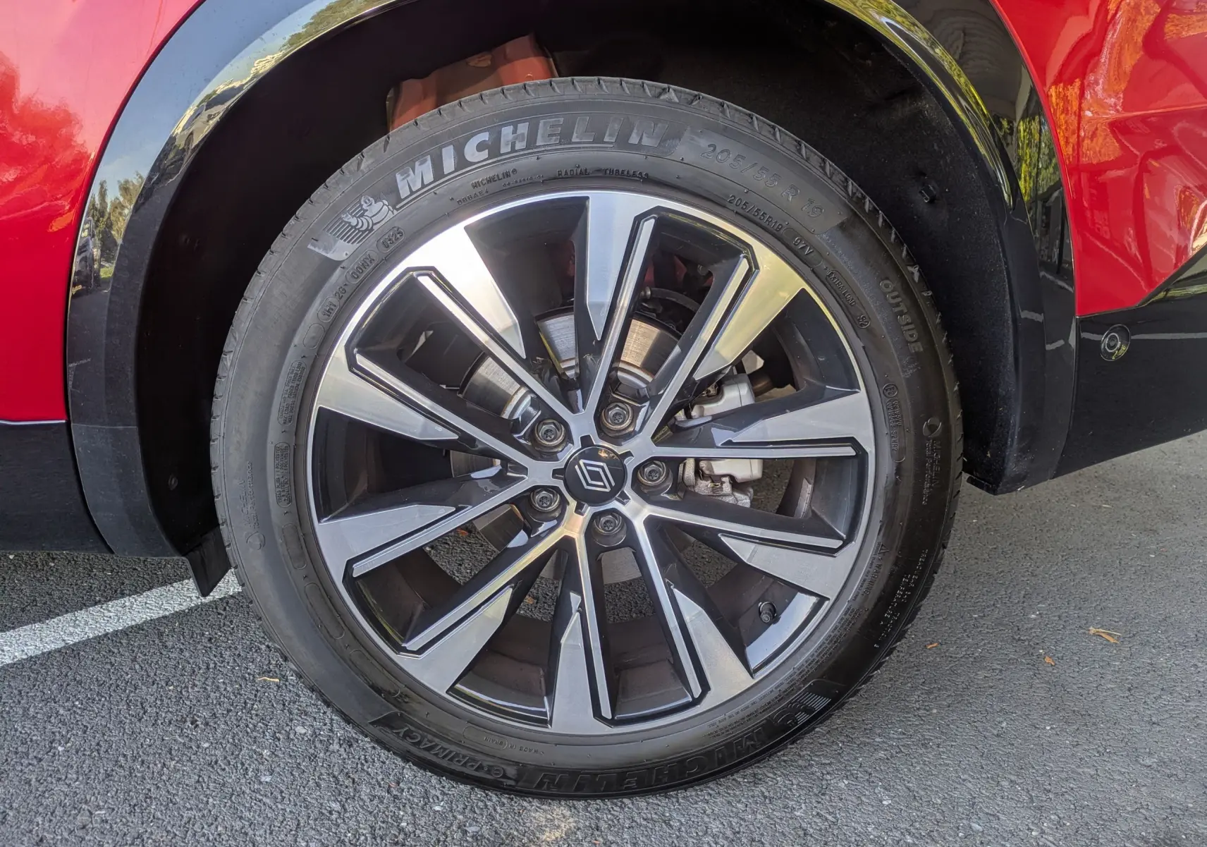 Gros plan sur la roue avant droite du Renault Austral rouge Flamme, avec jante alliage bicolore et pneu Michelin.