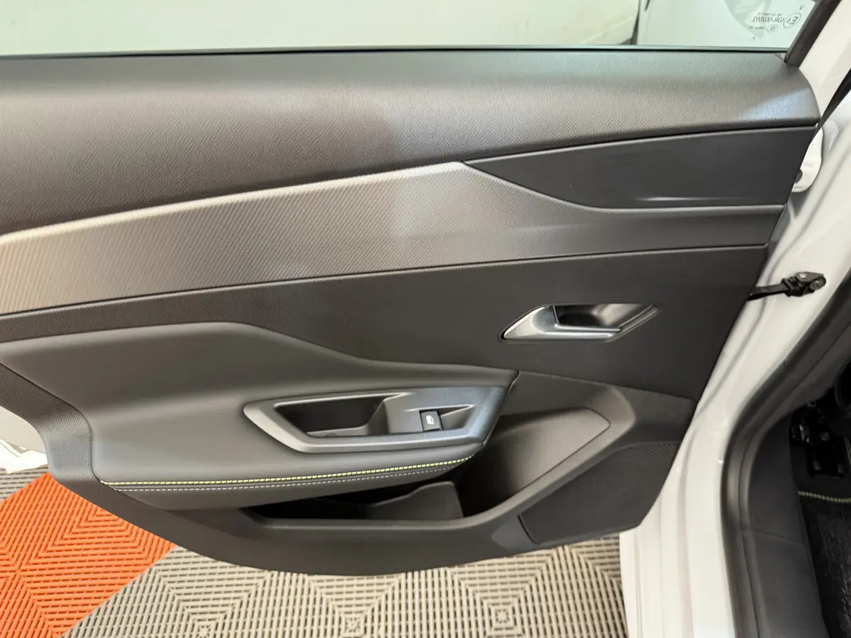 Porte intérieure côté avant gauche de la Peugeot 308 Hybrid blanche, avec garniture noire et surpiqûres vertes.
