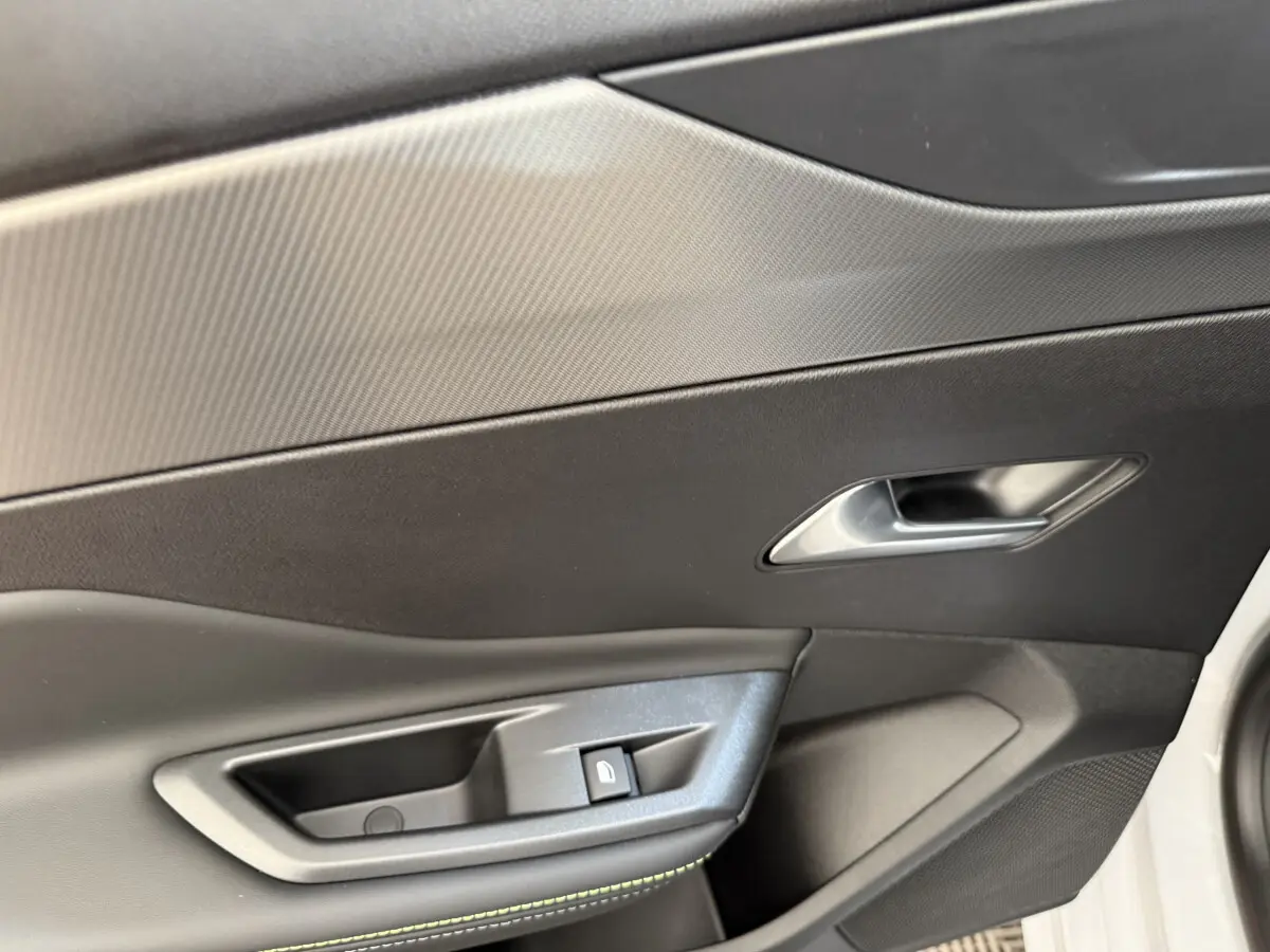 Détail de la porte côté conducteur de la Peugeot 308 Hybrid 136 e-DCS6 GT blanche avec bouton de verrouillage et poignée argentée.