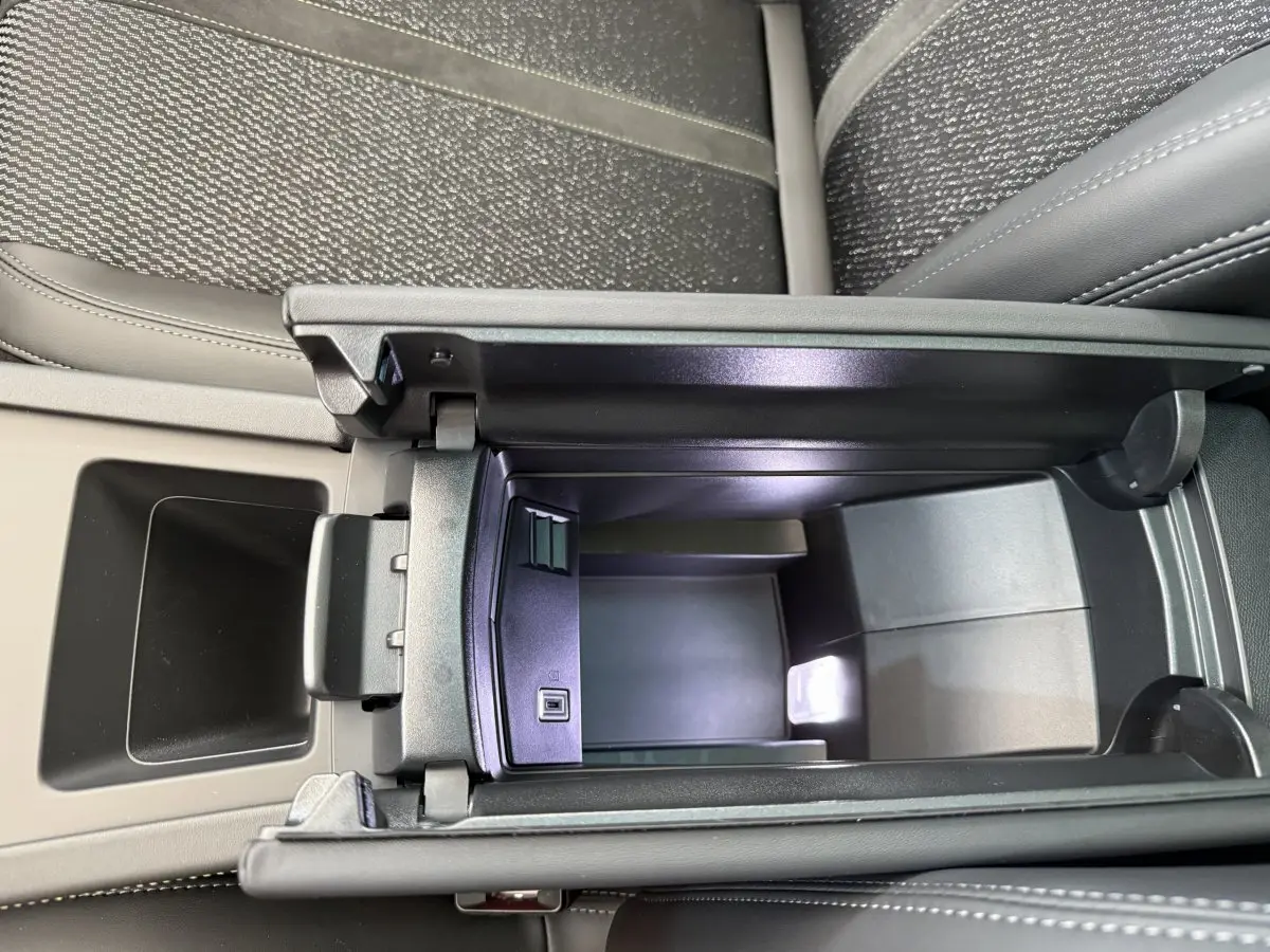 Vue plongeante sur la console centrale noire ouverte du Peugeot 308 Hybrid 136 e-DCS6 GT avec sellerie grise.