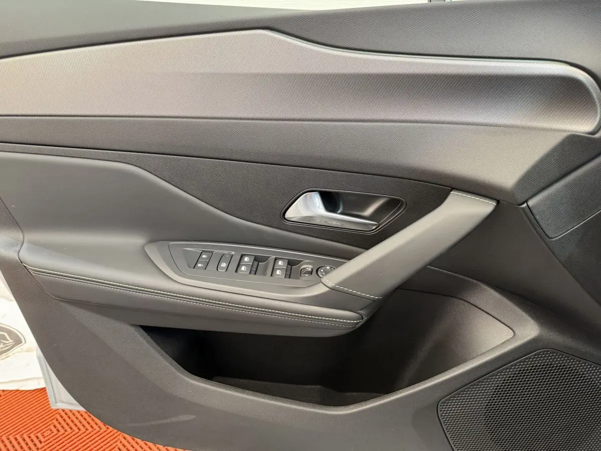 Vue rapprochée de la porte intérieure côté gauche de la Peugeot 308 Hybrid 136 e-DCS6 GT 2024 avec commandes et poignée grises.