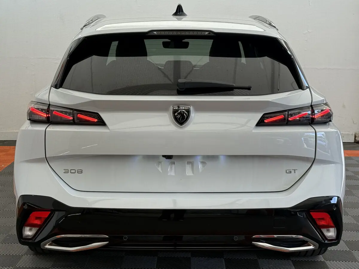 Vue arrière d'une Peugeot 308 GT blanche avec feux LED distinctifs et double sortie d'échappement chromée.