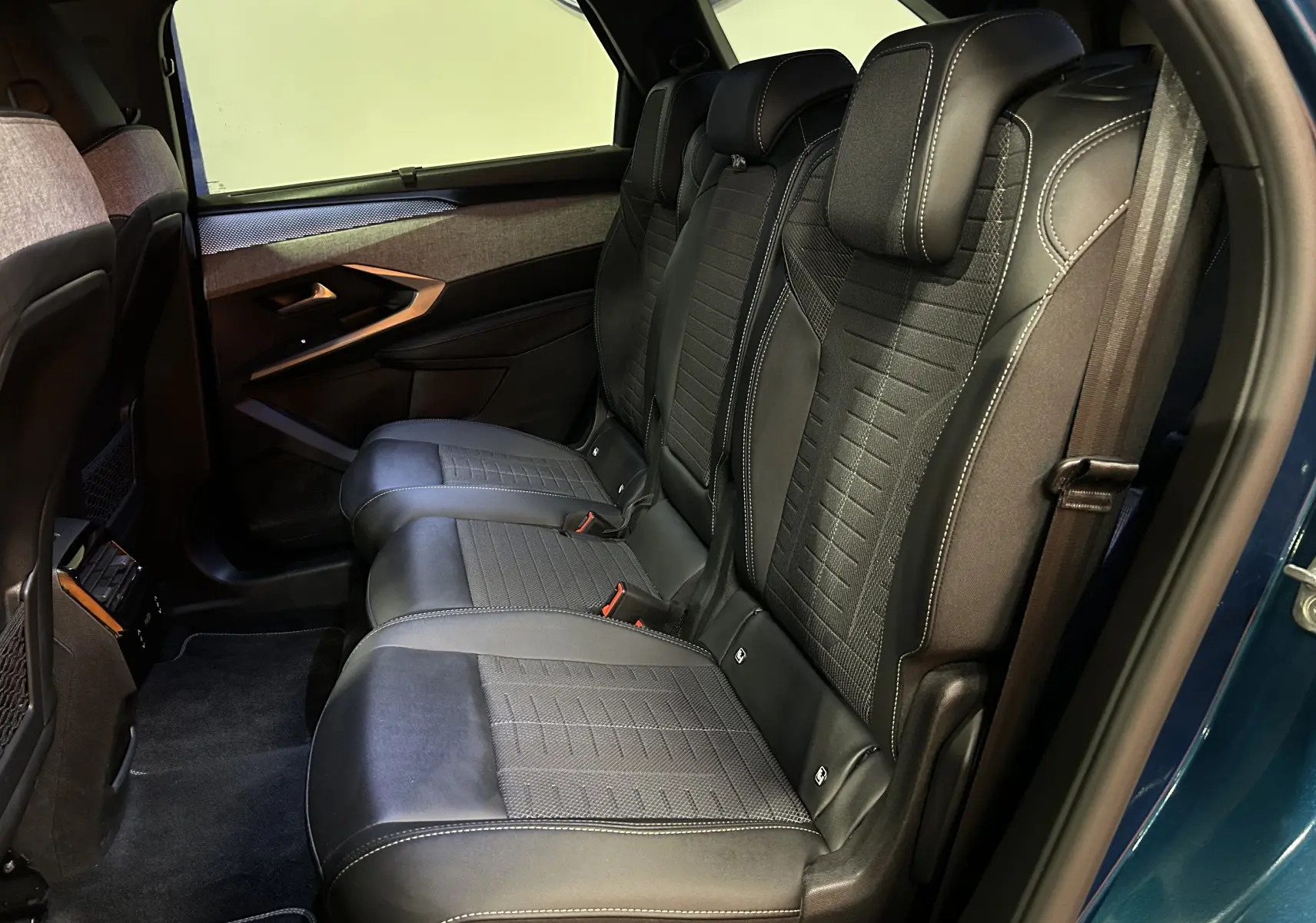 Vue intérieure côté gauche des sièges arrière en cuir noir du Peugeot 5008 III HYBRID 145 e-DSC6 GT Bleu Obsession.