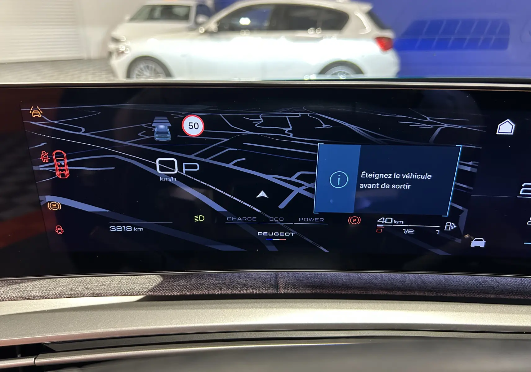 Tableau de bord numérique du Peugeot 5008 hybride 2025 affichant la navigation et alertes, intérieur moderne en tissu gris.