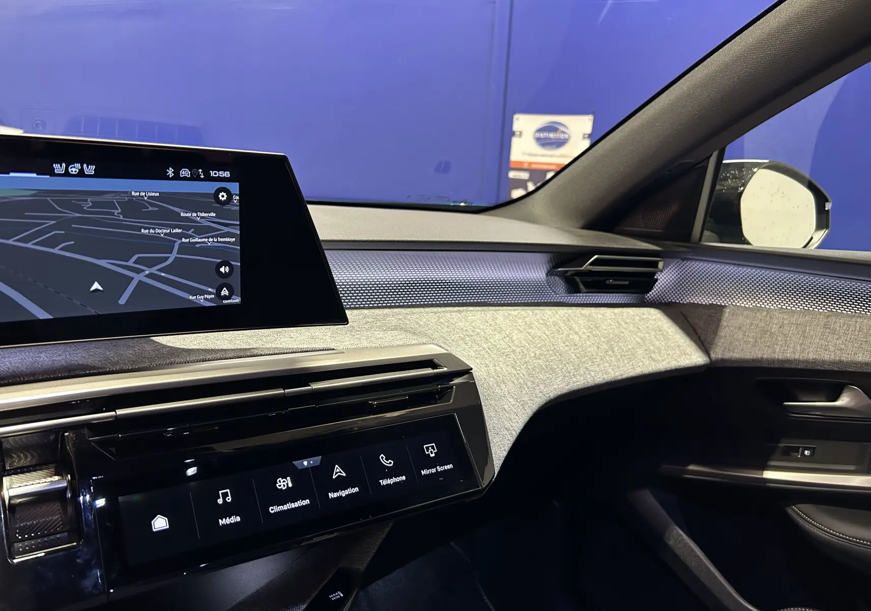 Vue intérieure côté passager du tableau de bord du Peugeot 5008 Hybrid 2025 avec écran tactile et habillage gris texturé.