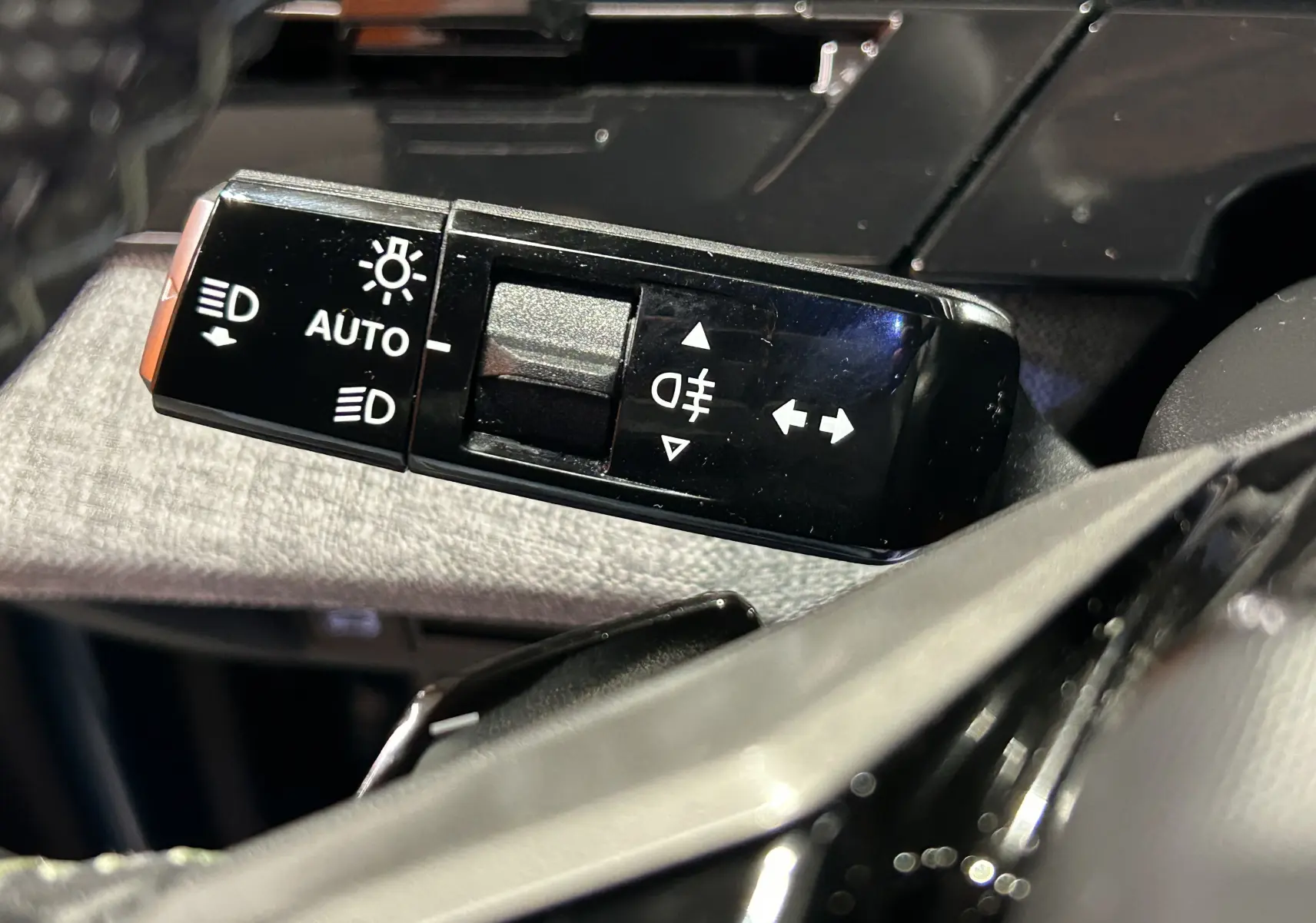 Gros plan sur la commande des feux et clignotants du Peugeot 5008 III Hybrid 145 e-DSC6 GT, intérieur noir.