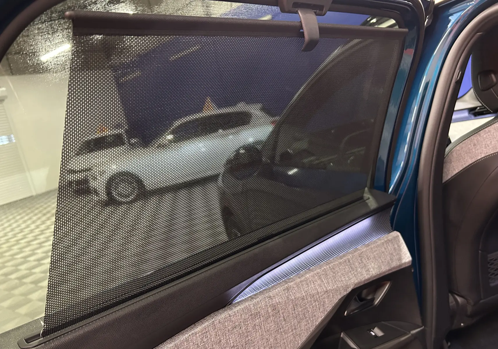 Vue intérieure de la porte arrière droite du Peugeot 5008 bleu Obsession avec pare-soleil intégré et éclairage d’ambiance.