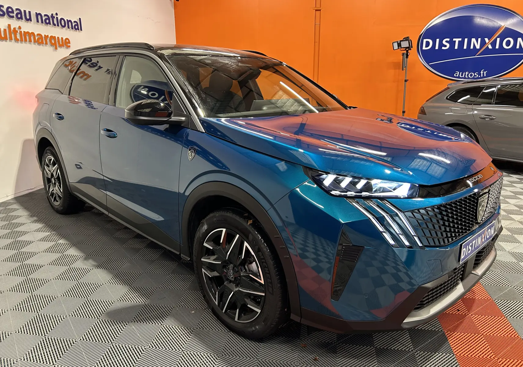 Peugeot 5008 III Hybrid 145 GT bleu obsession en 3/4 avant droit, avec phares LED et jantes noires distinctives.