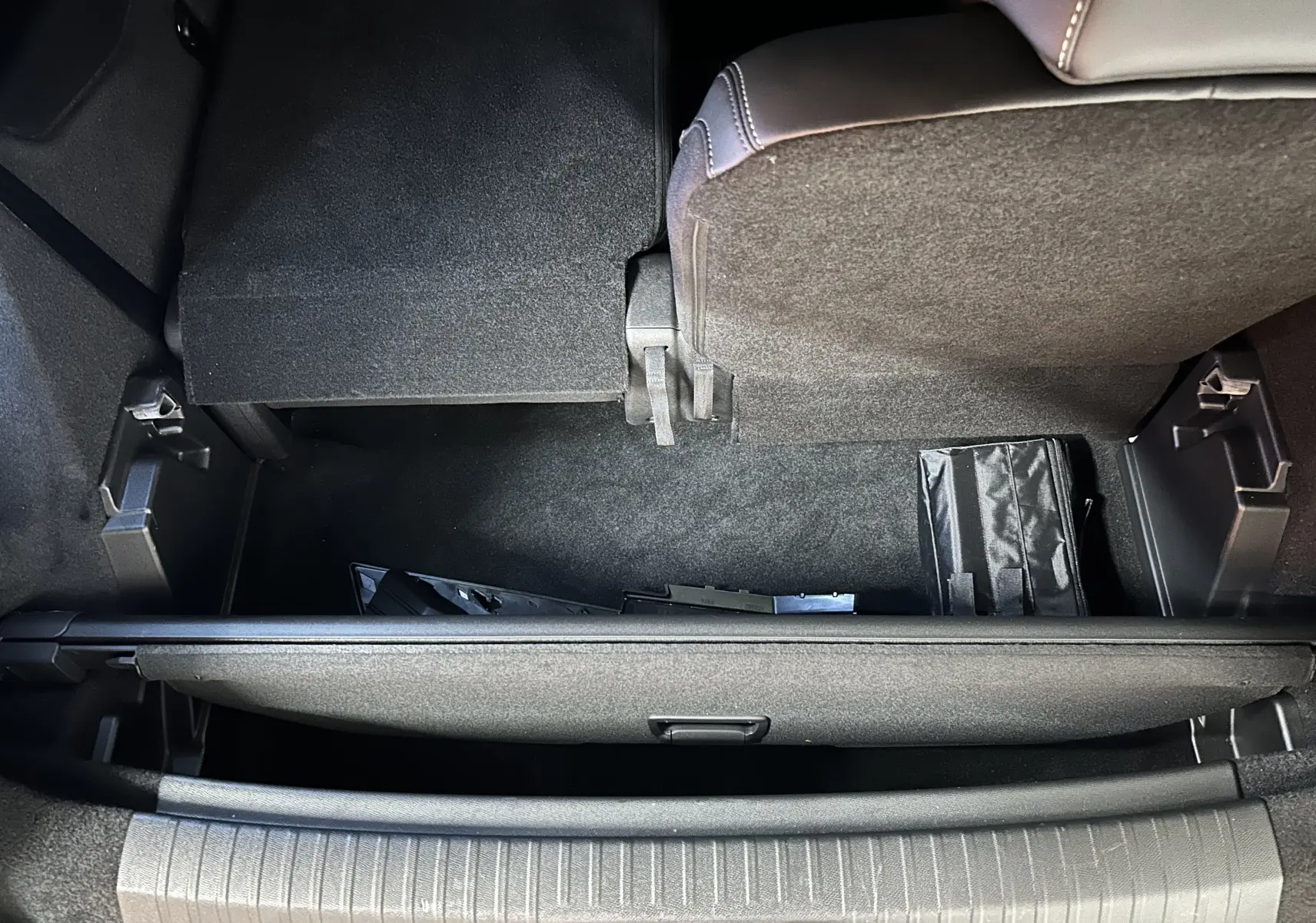 Vue plongeante sur le coffre arrière du Peugeot 5008 III Hybrid 145 GT en bleu Obsession, montrant le plancher relevé et rangement.