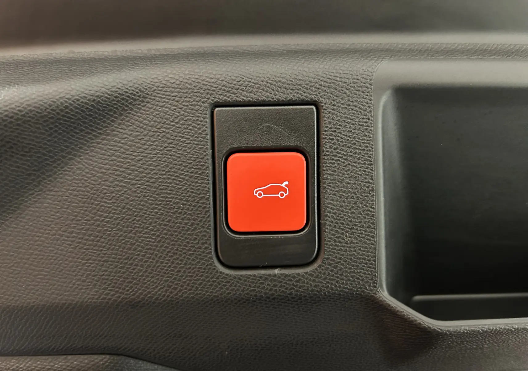 Bouton rouge d'ouverture électrique du hayon sur le panneau intérieur d'un Peugeot 5008 Bleu Obsession 2025.